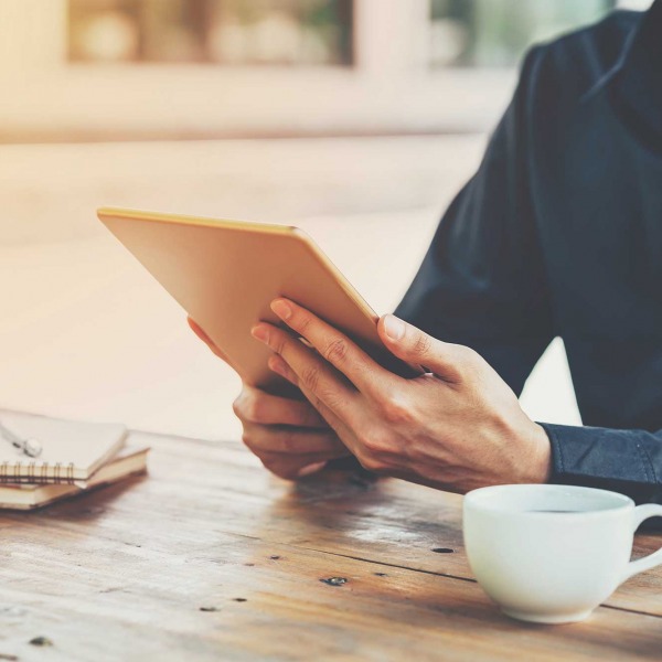 Man accessing Blue Wren's employee engagement platform on a tablet sat at a table