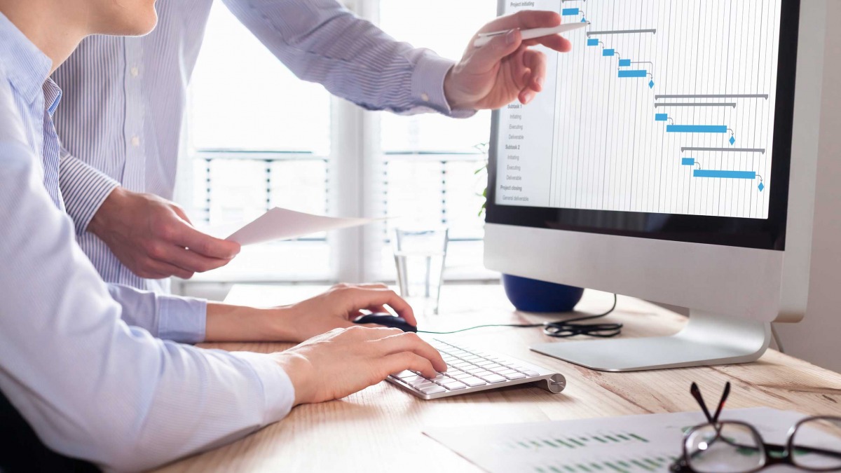 A male and female looking at a chart on a Mac computer