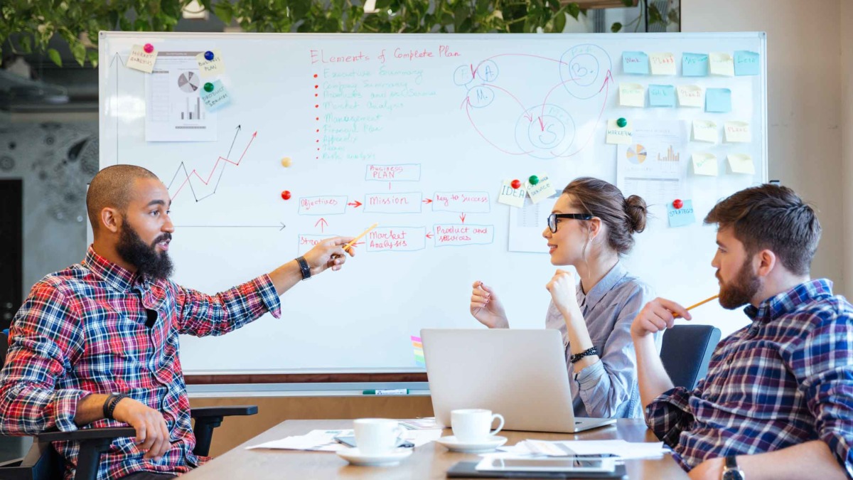 Team of people discussing their business processes, mapping them on a whiteboard