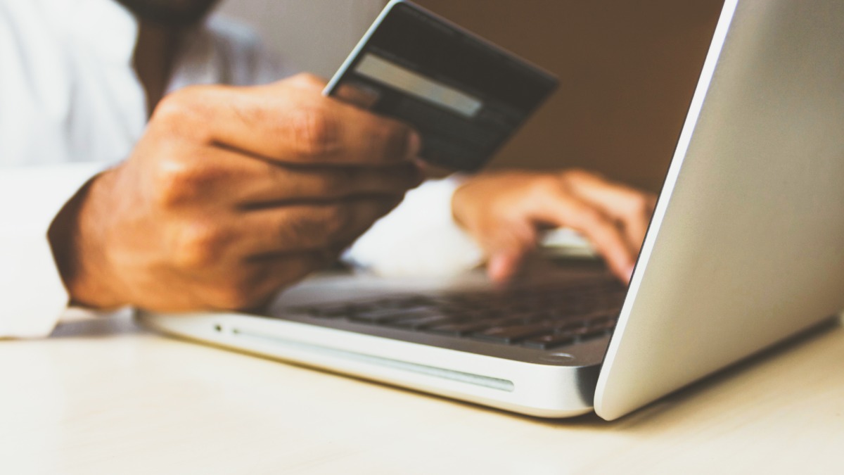 Customer in front of a laptop using their card to pay via an ecommerce transaction